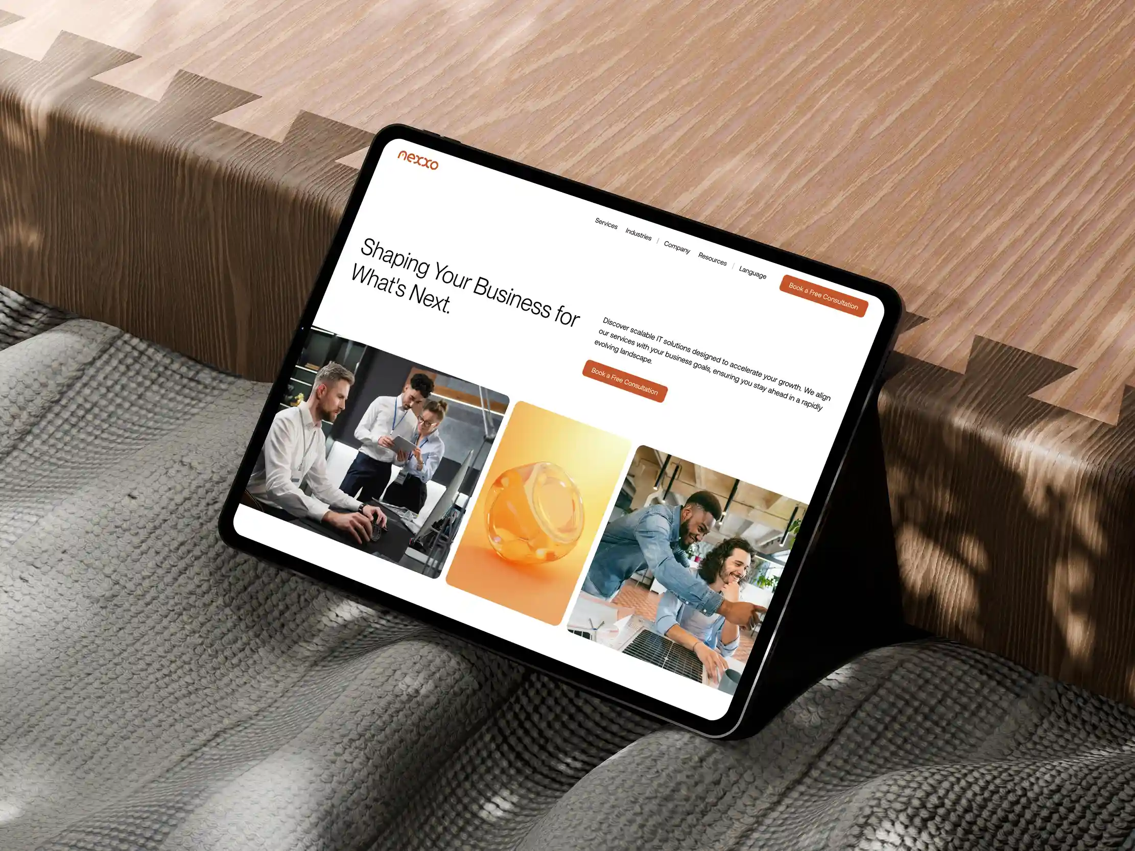 Tablet displaying Nexxo website homepage with business-related images and text about scalable IT solutions on a soft textured surface.
